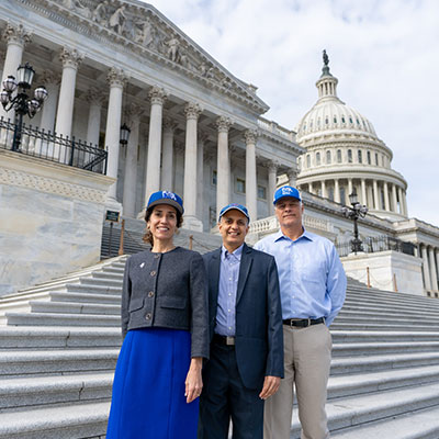 Drs. Carmen Astorne and P.K. Jain and Ted White from UofM Athletics standing on the steps of the Capitol Building in D.C.