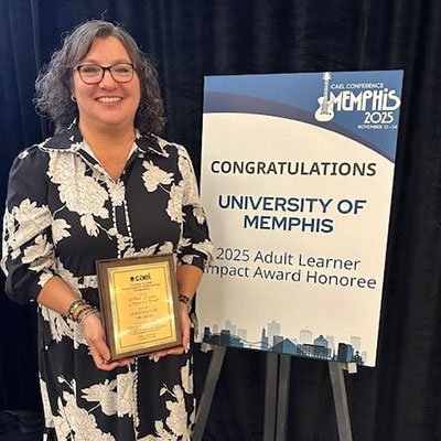 Tracy Robinson standing with award and sign