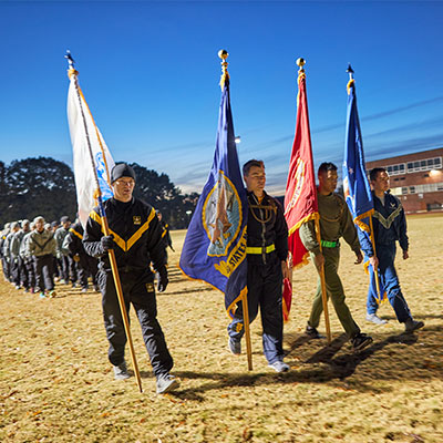 Miltary flags lead a group of military students