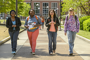 four student walking side by side on campus