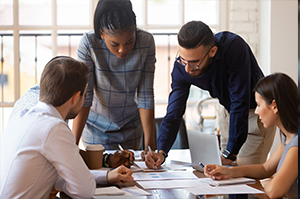 accountants gather around table to look at papers