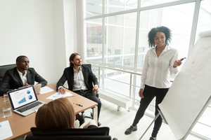 female professional presenting to group of colleagues