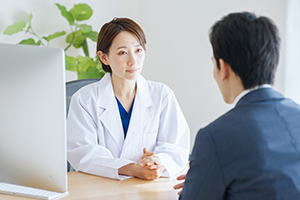 professional wearing lab coat talking to man with back turned to camera