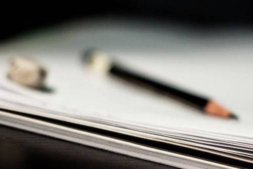 a pencil out-of-focus on a stack of paper